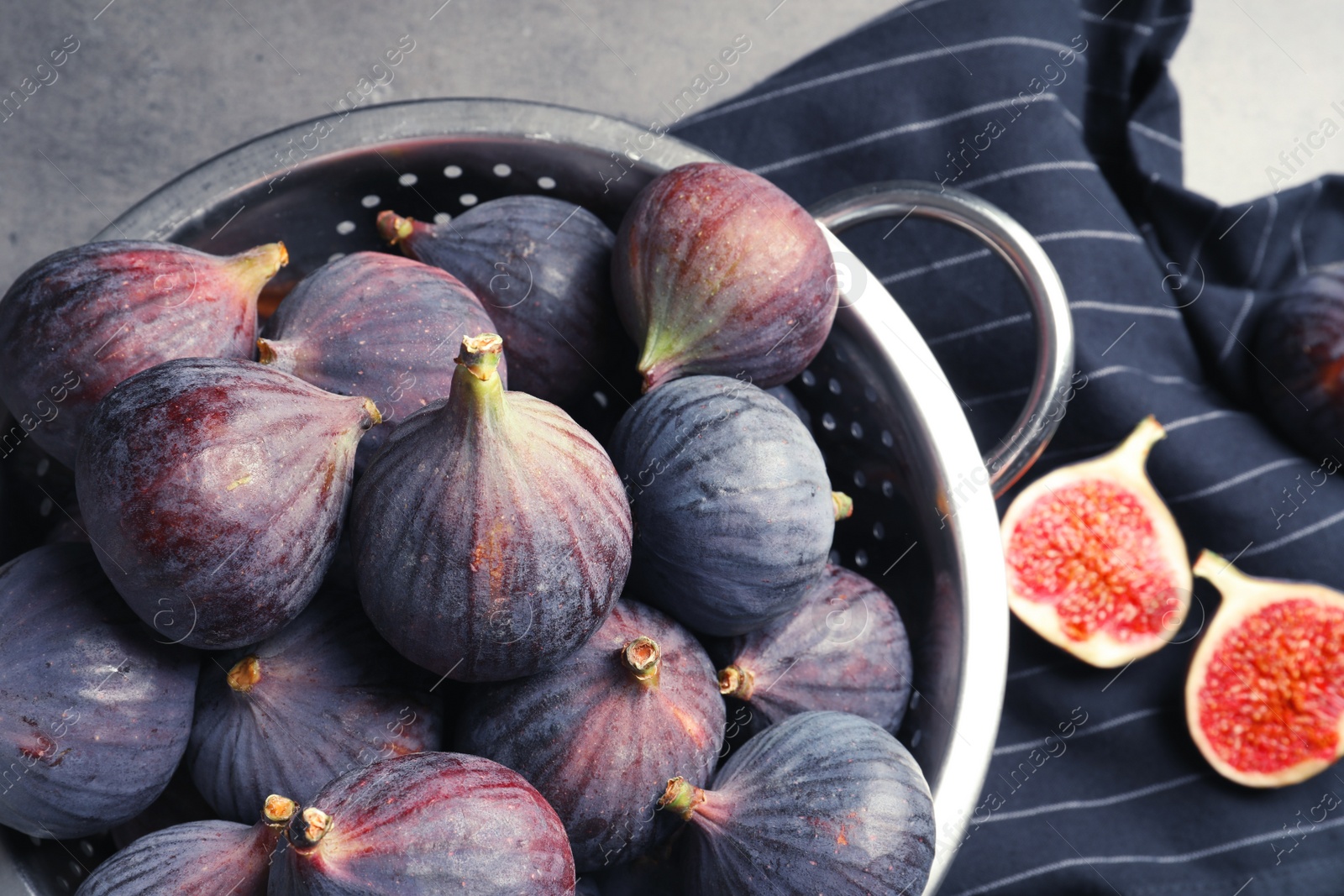 Photo of Colander with fresh ripe figs on gray background