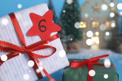 Photo of Gift boxes with paper tag near festive decor on light blue background, closeup. December, 6 - Saint Nicholas Day