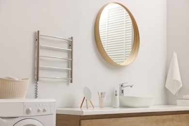 Photo of Stylish bathroom interior with heated towel rail and washing machine
