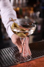 Bartender with fresh Martini cocktail at bar counter, closeup