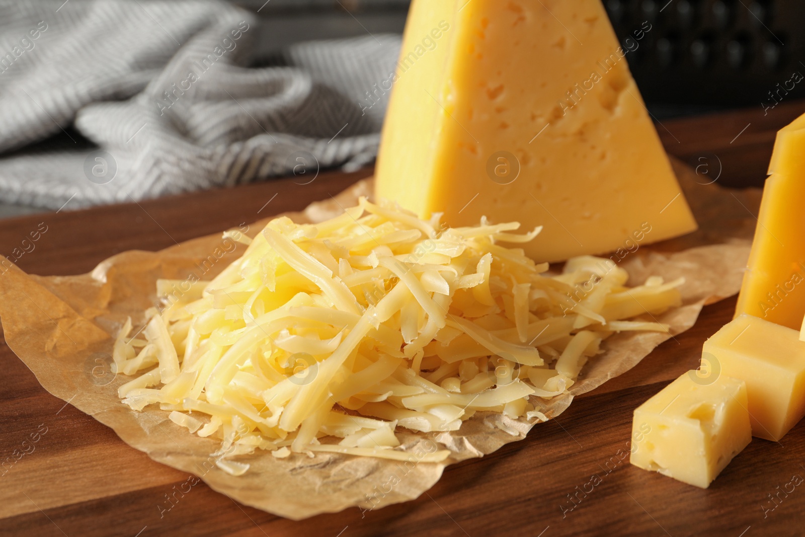 Photo of Grated and cut delicious cheese on board, closeup