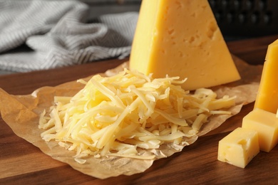 Photo of Grated and cut delicious cheese on board, closeup