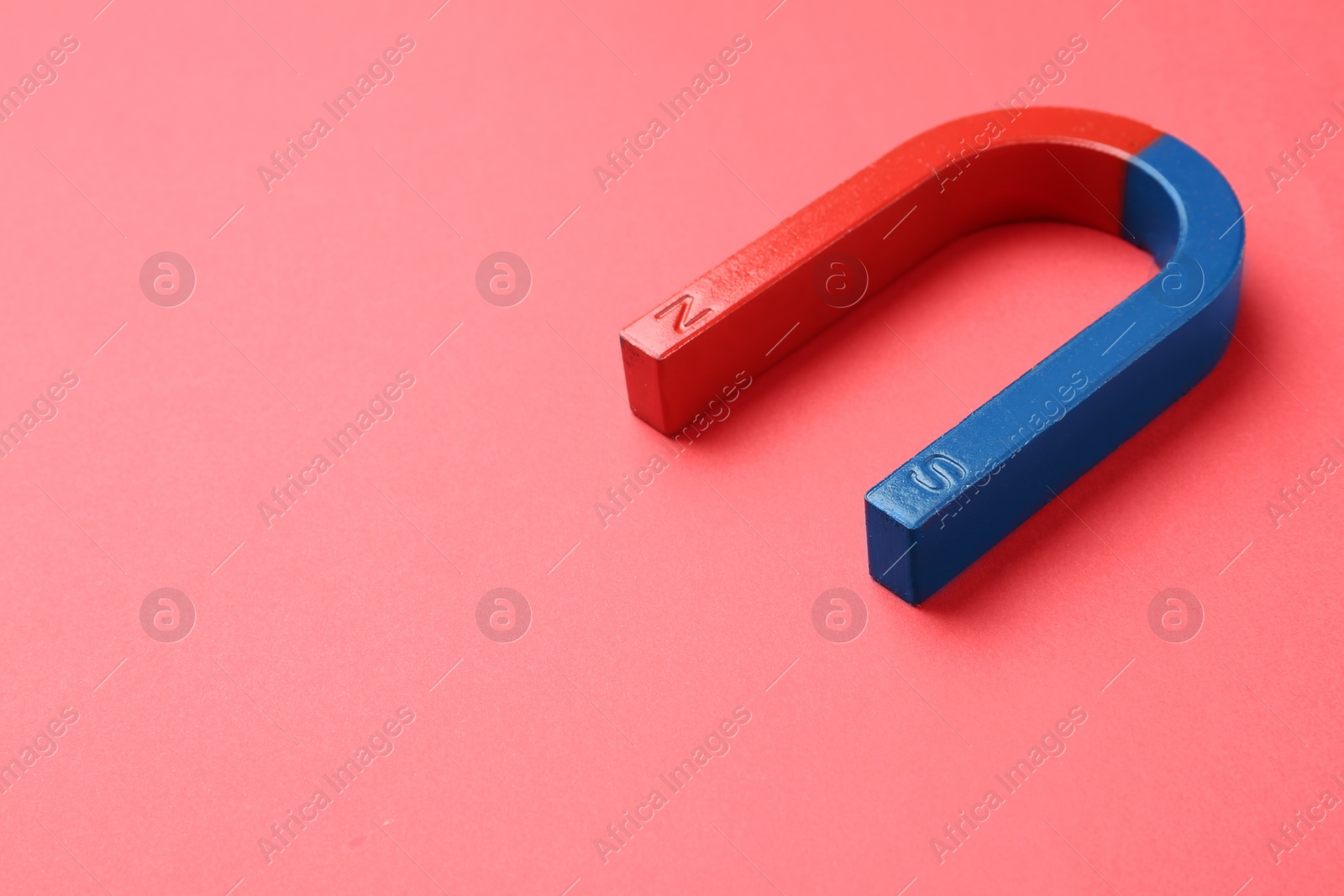 Photo of Red and blue horseshoe magnet on color background. Space for text