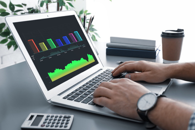 Broker using modern laptop at table, closeup. Forex trading