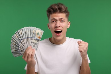 Photo of Handsome man with dollar banknotes on green background