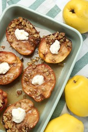 Tasty baked quinces with nuts and cream cheese in dish on table, flat lay