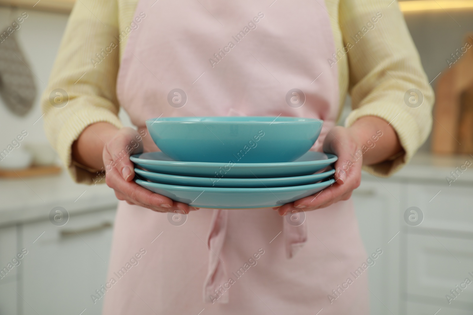 Photo of Woman holding plates in kitchen, closeup view