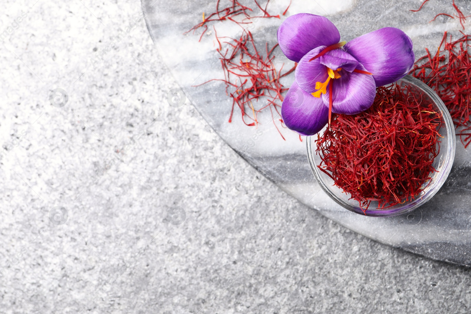 Photo of Dried saffron in bowl and crocus flowers on grey table, flat lay. Space for text