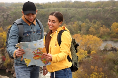 Couple of travelers with backpacks and map planning trip in mountains. Autumn vacation