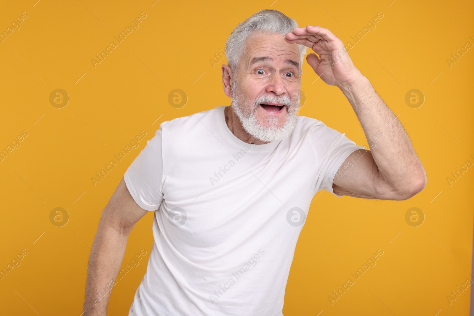 Photo of Portrait of surprised senior man on yellow background