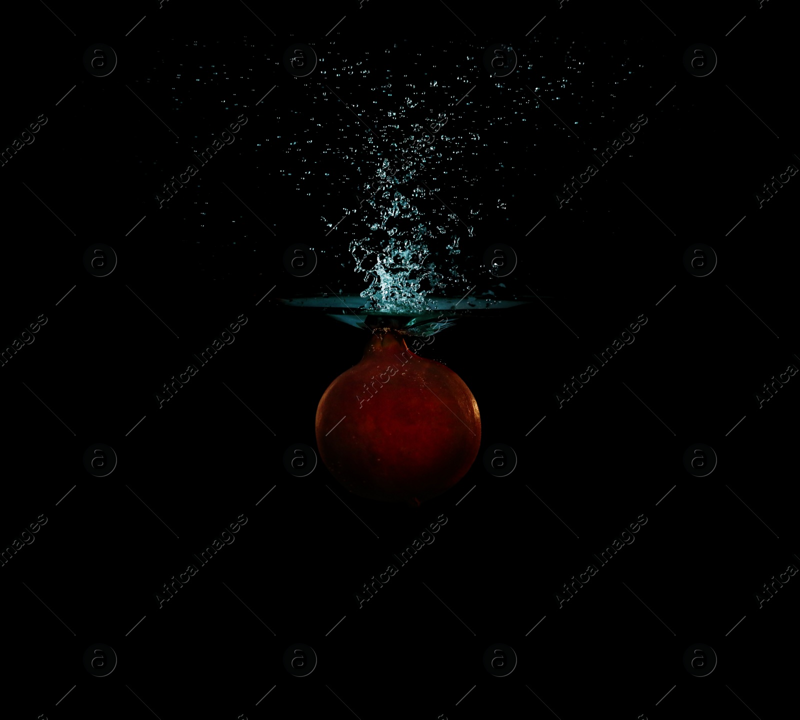 Photo of Pomegranate falling down into clear water against black background