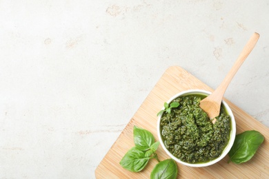 Photo of Board with homemade basil pesto sauce in bowl on table, top view. Space for text