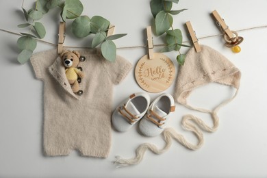 Photo of Baby clothes, shoes and accessories with washing line on light background, flat lay