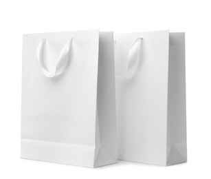 Paper shopping bags with ribbon handles on white background. Mockup for design