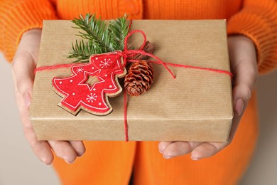 Christmas present. Woman holding beautifully wrapped gift box on beige background, closeup