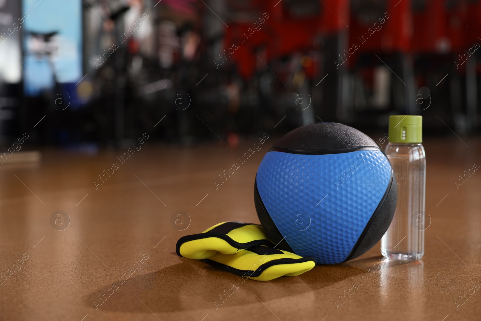 Photo of Medicine ball, bottle and weighting agents on floor in gym. Space for text