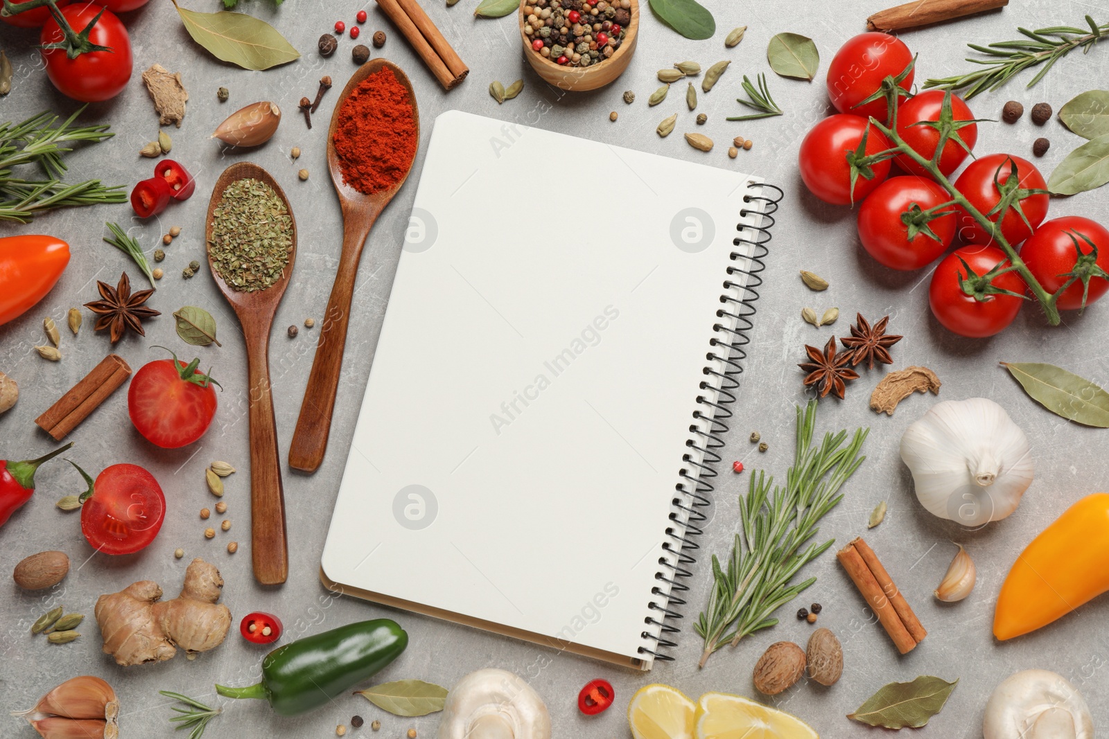 Photo of Open recipe book and different ingredients on grey table, flat lay. Space for text