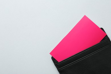 Leather business card holder with colorful cards on light grey background, top view. Space for text