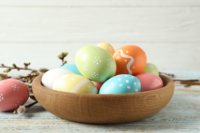 Plate with painted Easter eggs on table against wooden background