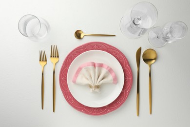 Stylish setting with cutlery, napkin and plates on white textured table, flat lay