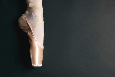 Photo of Ballerina in pointe shoe on black background, closeup. Space for text