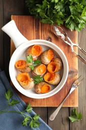 Delicious cooked snails served on wooden table, flat lay