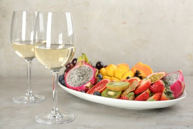 Delicious exotic fruits and wine on grey table