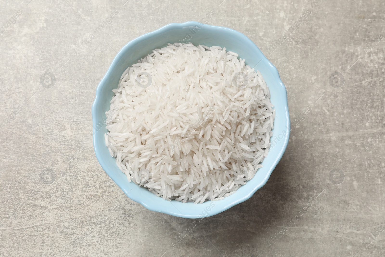 Photo of Raw basmati rice in bowl on grey table, top view