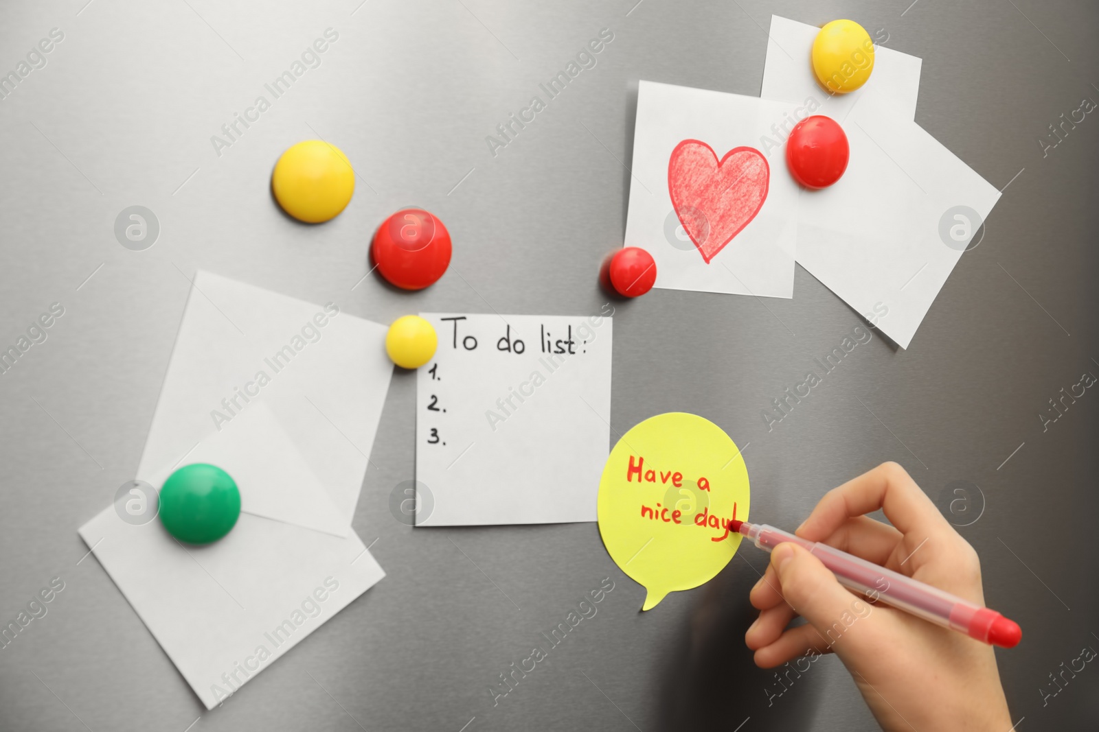 Photo of Woman writing message on note stuck to refrigerator door, closeup