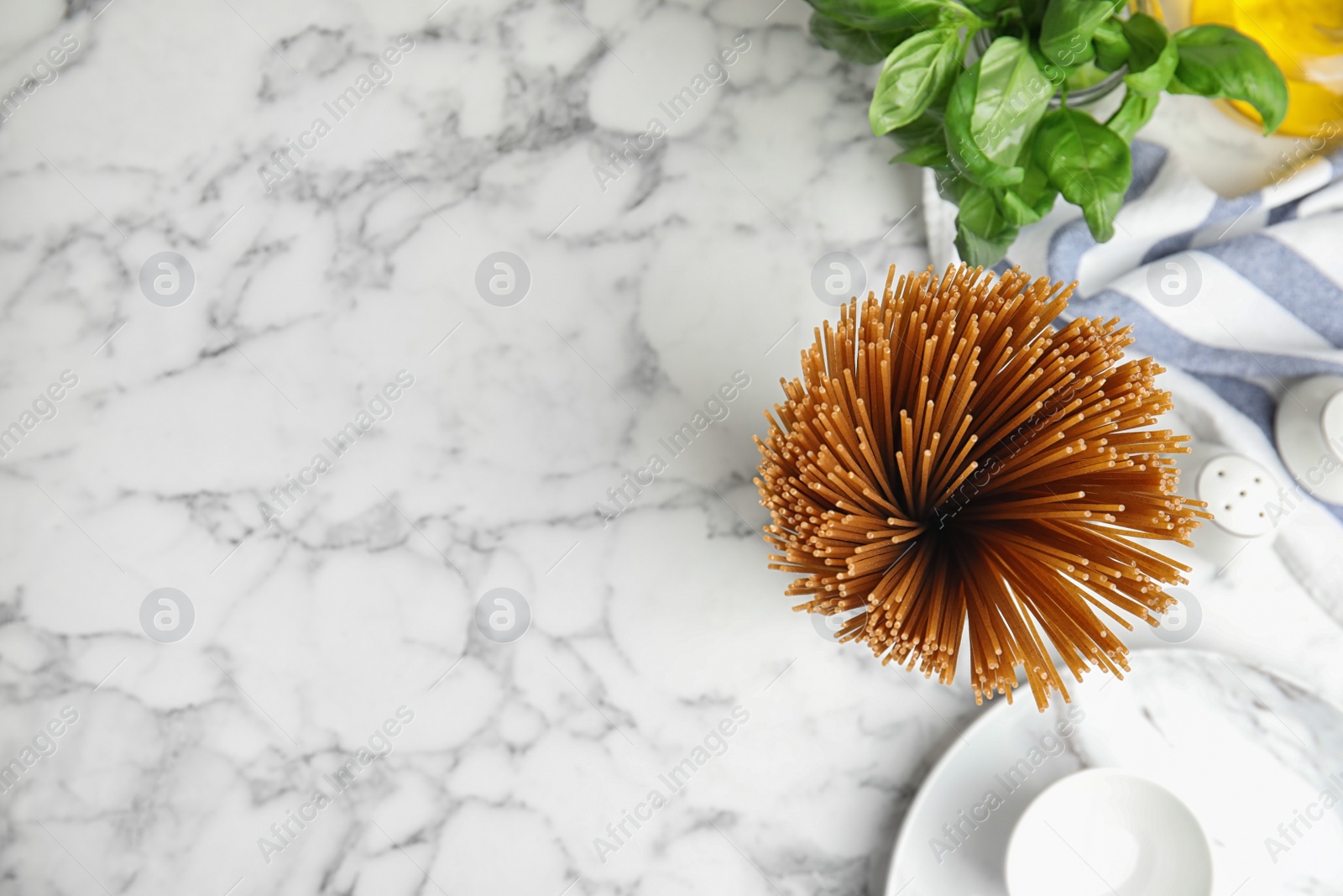 Photo of Uncooked buckwheat noodles on white marble table, flat lay. Space for text