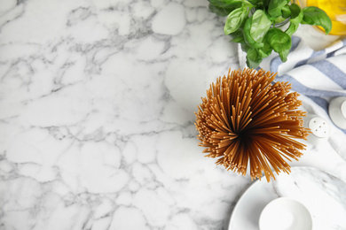 Photo of Uncooked buckwheat noodles on white marble table, flat lay. Space for text