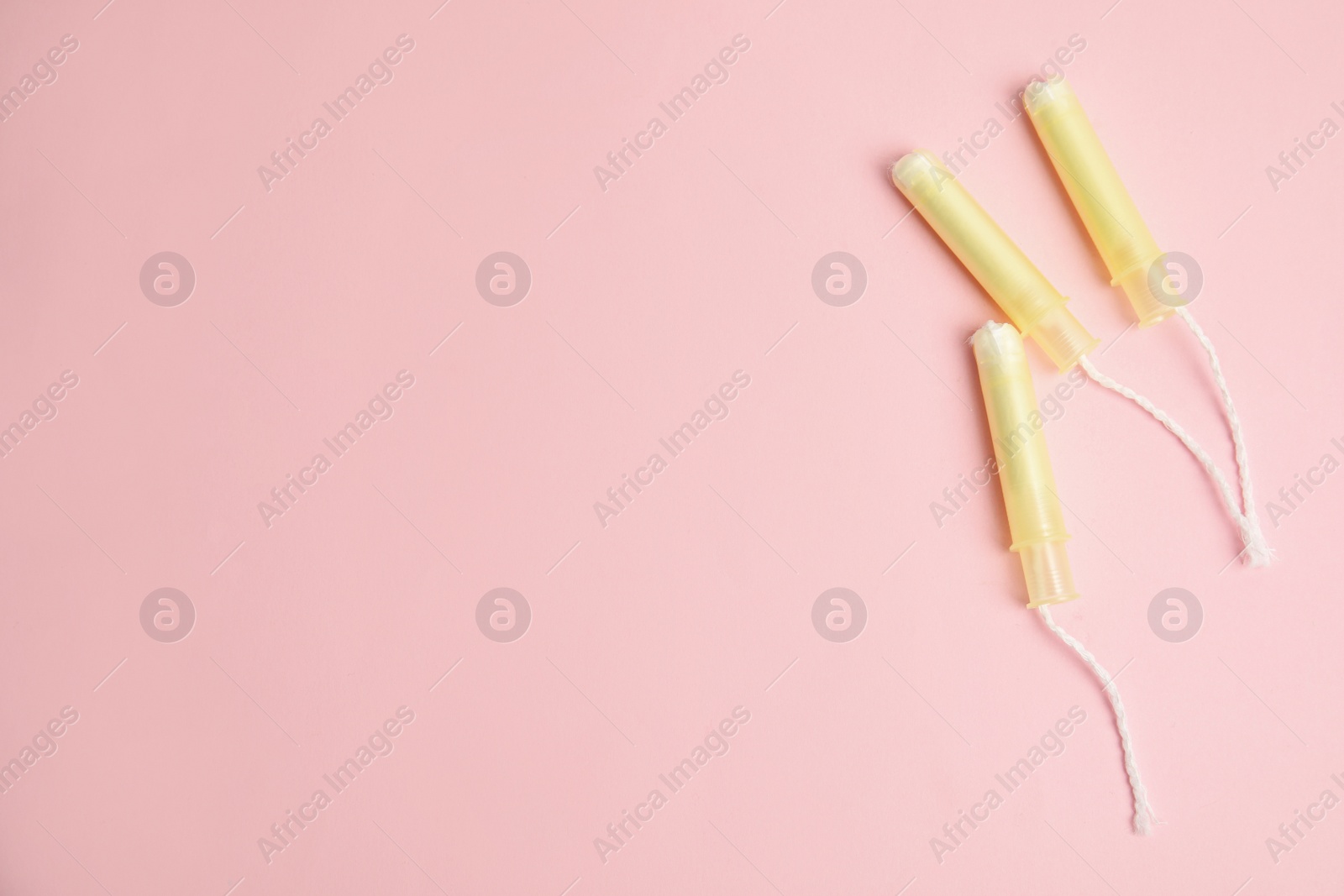 Photo of Tampons on light pink background, flat lay. Space for text