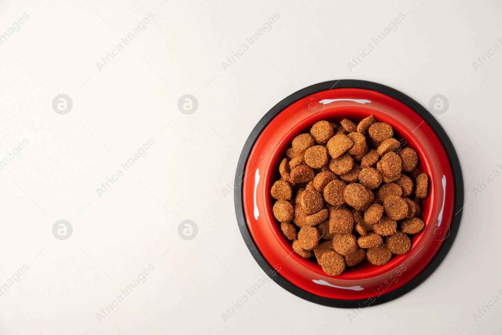 Photo of Dry dog food in feeding bowl on beige background, top view. Space for text