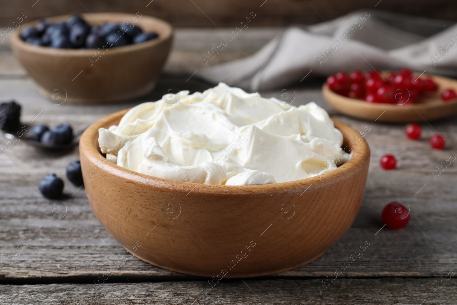Photo of Tasty cream cheese and fresh berries on wooden table