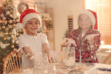 Photo of Cute little children having fun while making delicious Christmas cookies at home