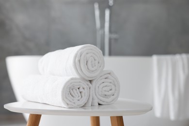 Photo of Rolled white towels on stool in bathroom. Space for text