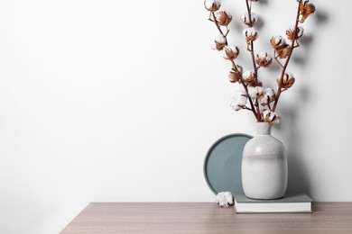 Photo of Book and vase with cotton branches on wooden table against white background. Space for text