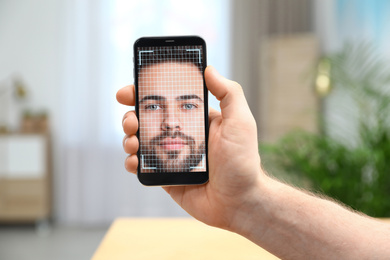 Image of Man using smartphone with facial recognition system indoors, closeup. Biometric verification