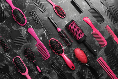 Photo of Flat lay composition with hair brushes and combs on black marble background