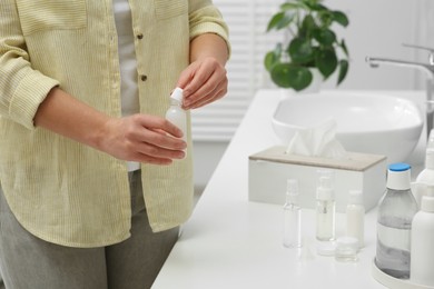 Woman with cosmetic travel kit in bathroom, closeup. Bath accessories