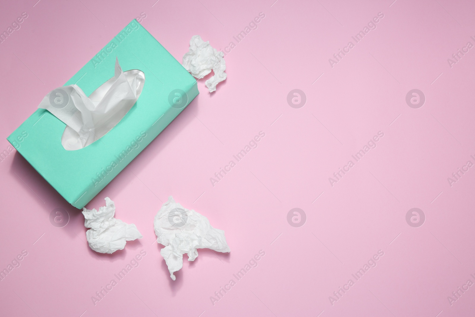 Photo of Used paper tissues and box on pink background, flat lay. Space for text