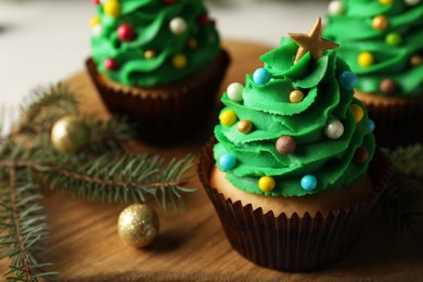 Photo of Tasty Christmas cupcakes on wooden board, closeup. Space for text