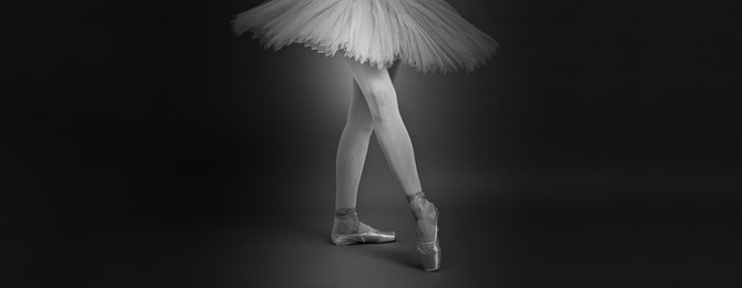 Image of Young ballerina in pointe shoes practicing dance moves, closeup. Black and white effect. Banner design