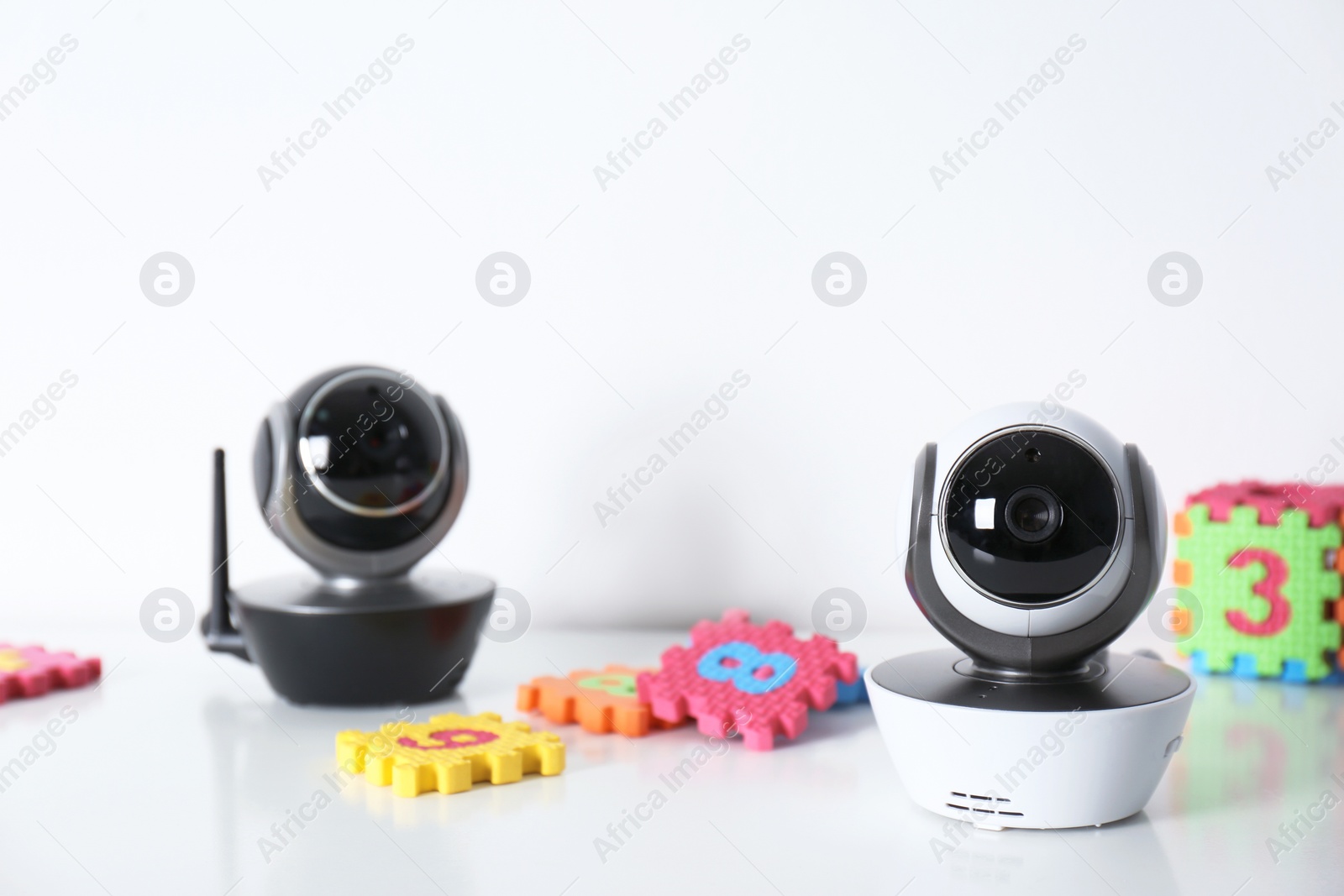 Photo of Modern CCTV security cameras and child puzzle on table against white background. Space for text