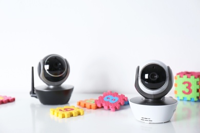 Photo of Modern CCTV security cameras and child puzzle on table against white background. Space for text