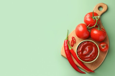 Photo of Bowl of tasty ketchup and ingredients on green table, top view. Space for text