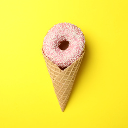 Photo of Ice cream made with donut on yellow background, top view