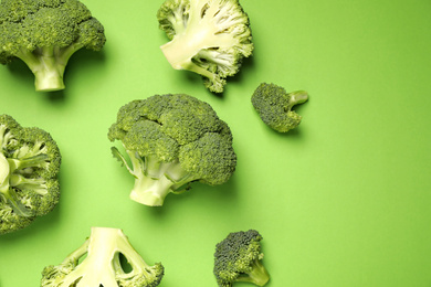 Photo of Fresh broccoli on green background, flat lay