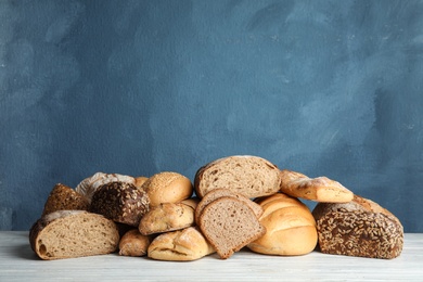 Pile of fresh bread on table against color background. Space for text