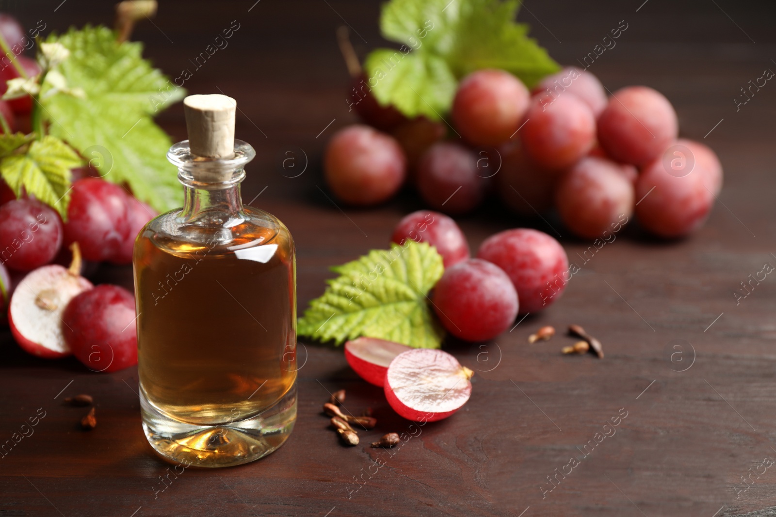 Photo of Bottle of natural grape seed oil on wooden table, space for text. Organic cosmetic